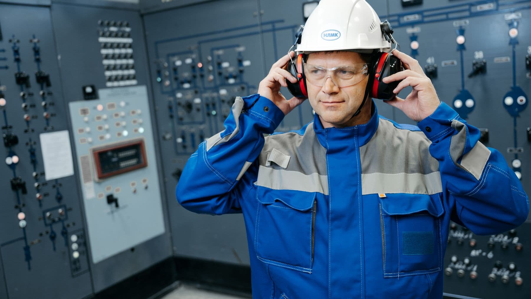 Engineer wearing protective gear in a control room, emphasizing safety and technology.